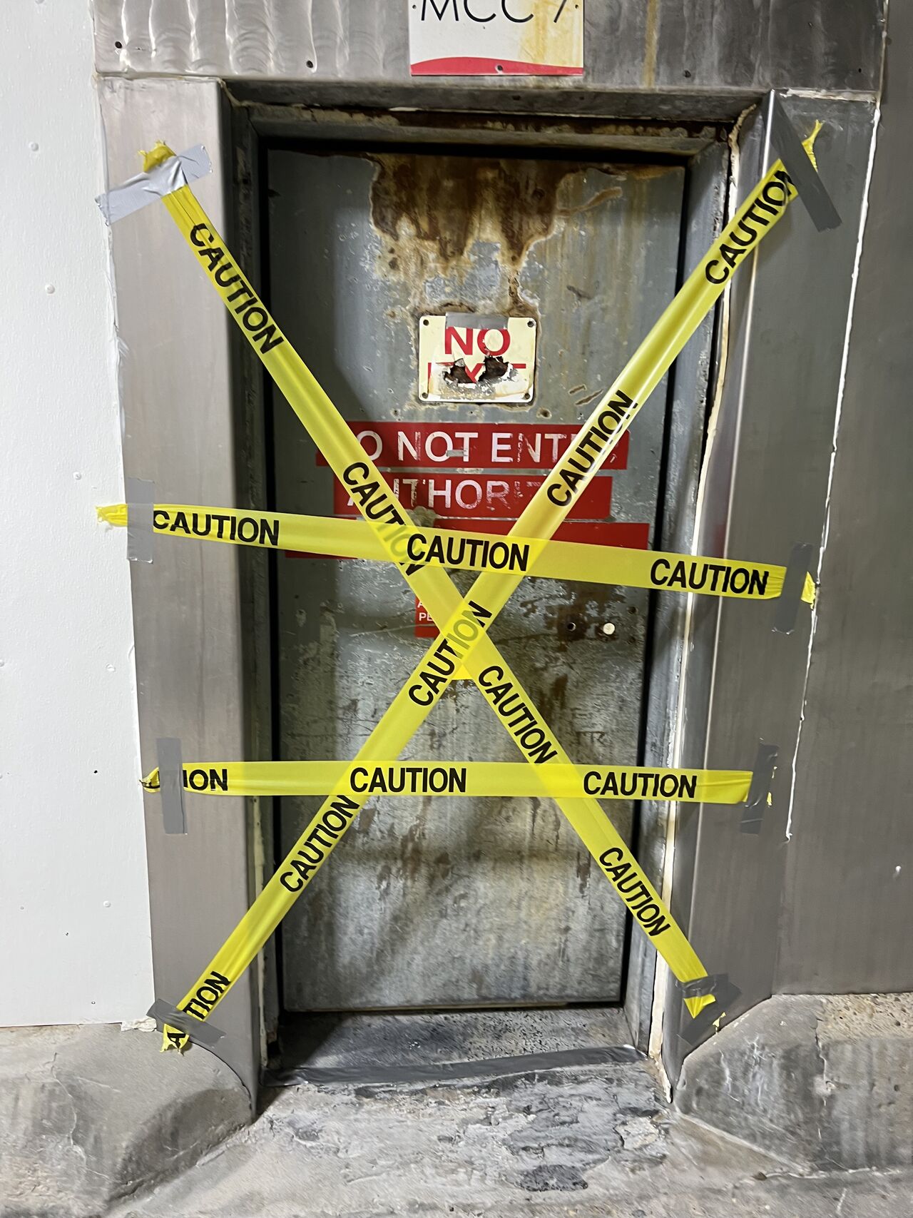 Door covered in multiple layers of caution tape and DO NOT ENTER signs at a food processing facility