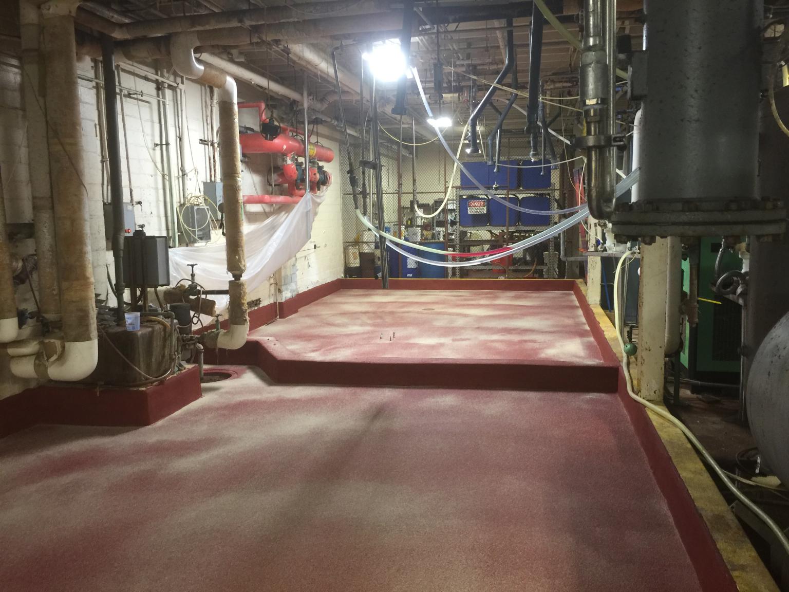Completed red SaniCrete SL floor with containment curbing in chemical storage room