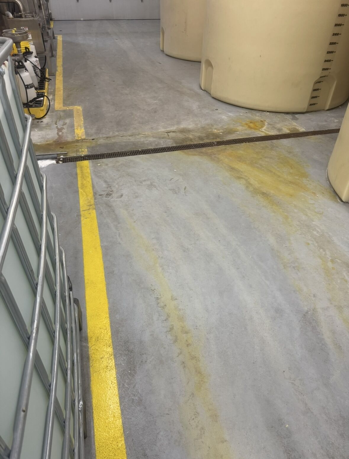 Chemical storage area with large tanks and deteriorating concrete floor with yellow line markings
