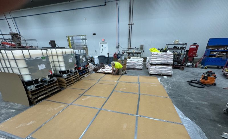 SaniCrete crew member laying protective cardboard and plastic sheeting before mixing concrete