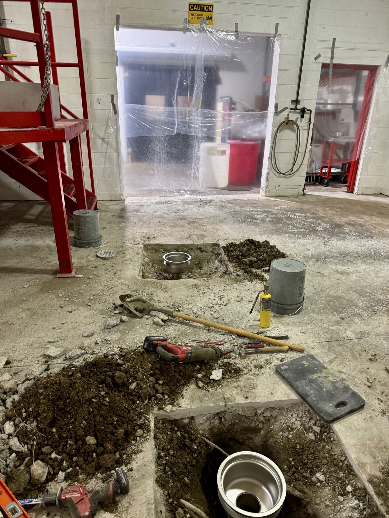 Concrete saw cut around drain locations with new round top drains and traps being installed in production room