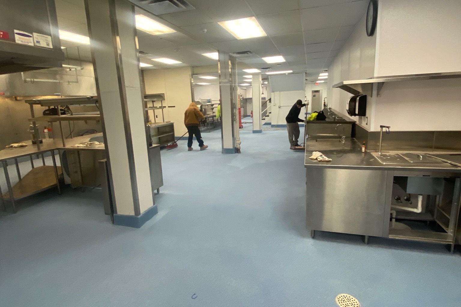 SaniCrete flooring installation in a commercial kitchen with stainless steel equipment and floor drain