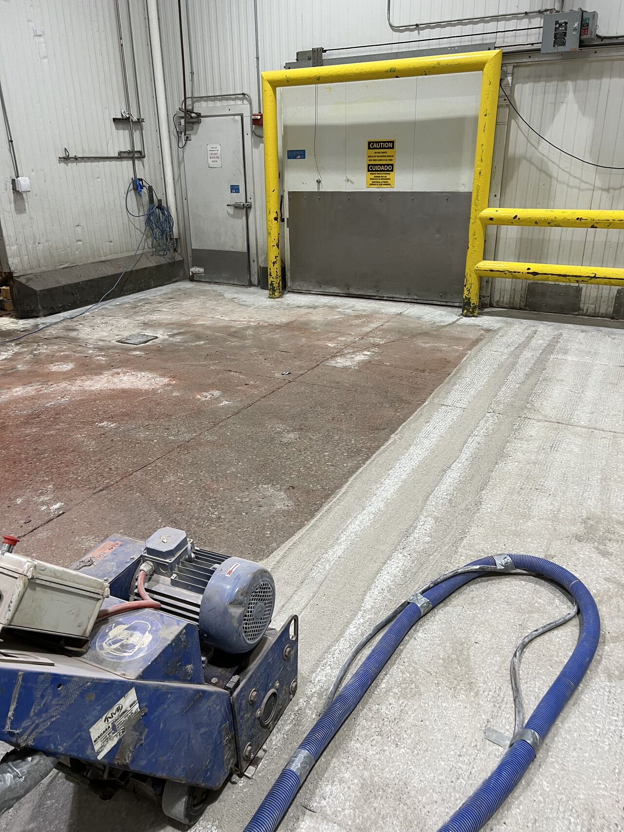 Scarifier with HEPA vacuum profiling concrete substrate at loading dock near dock door
