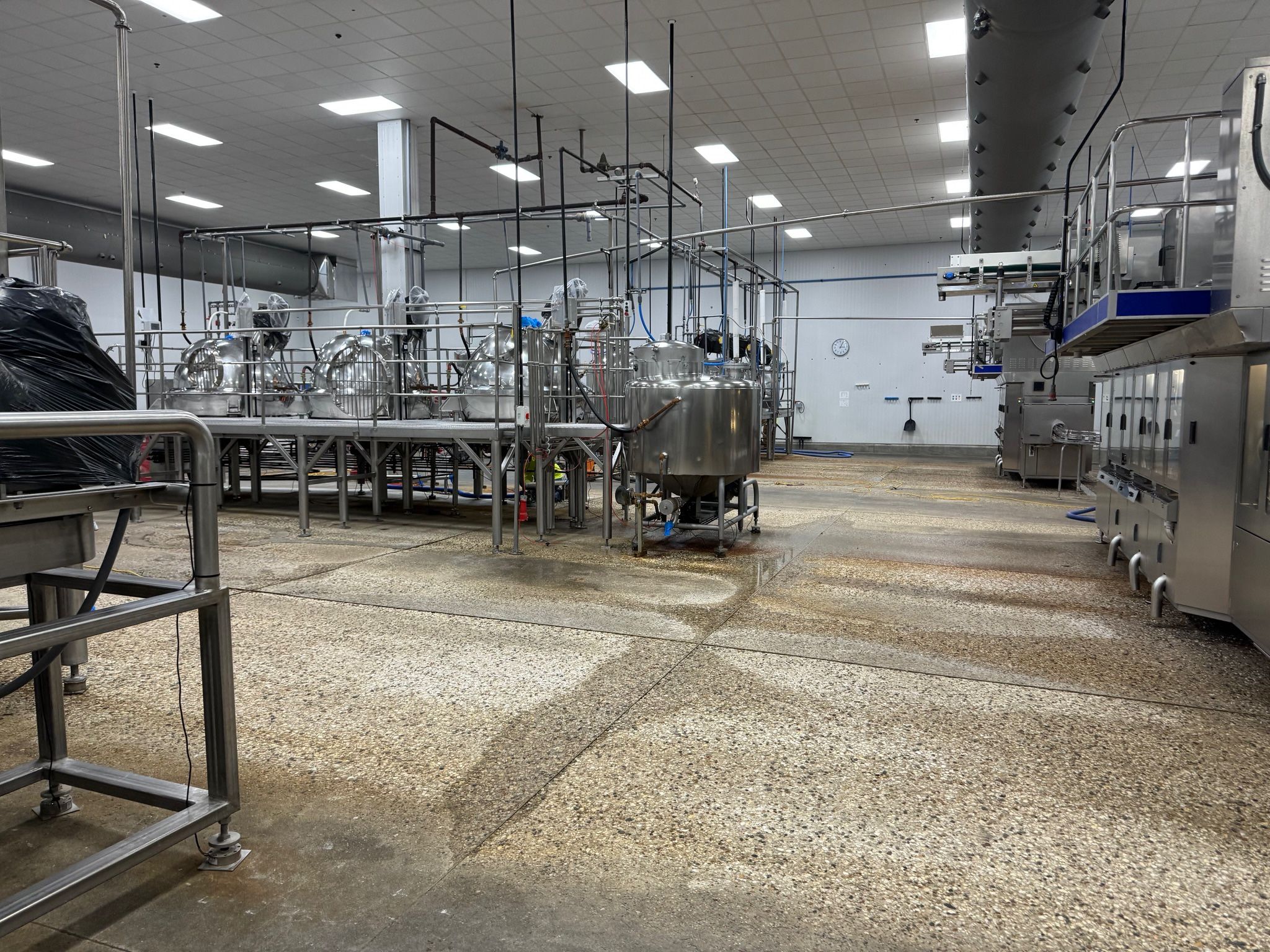 Food processing production room with deteriorating floor showing wear patterns and damage around equipment