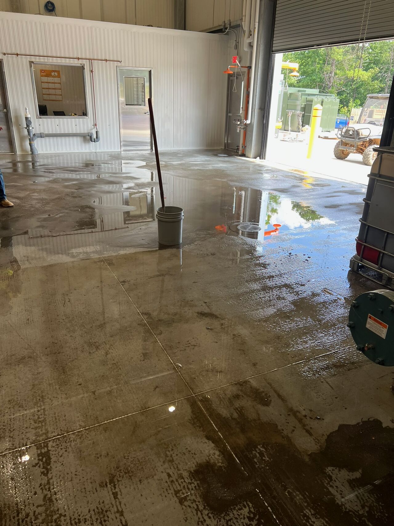 Engine room before — standing water pooling across bare concrete floor with drainage issues