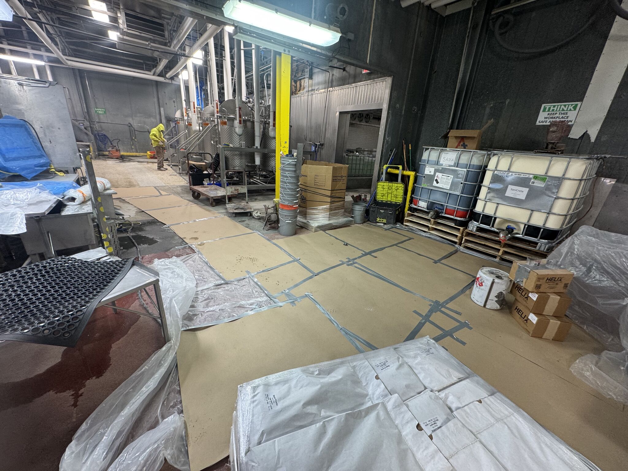 Production floor with cardboard protection over equipment during shutdown preparation