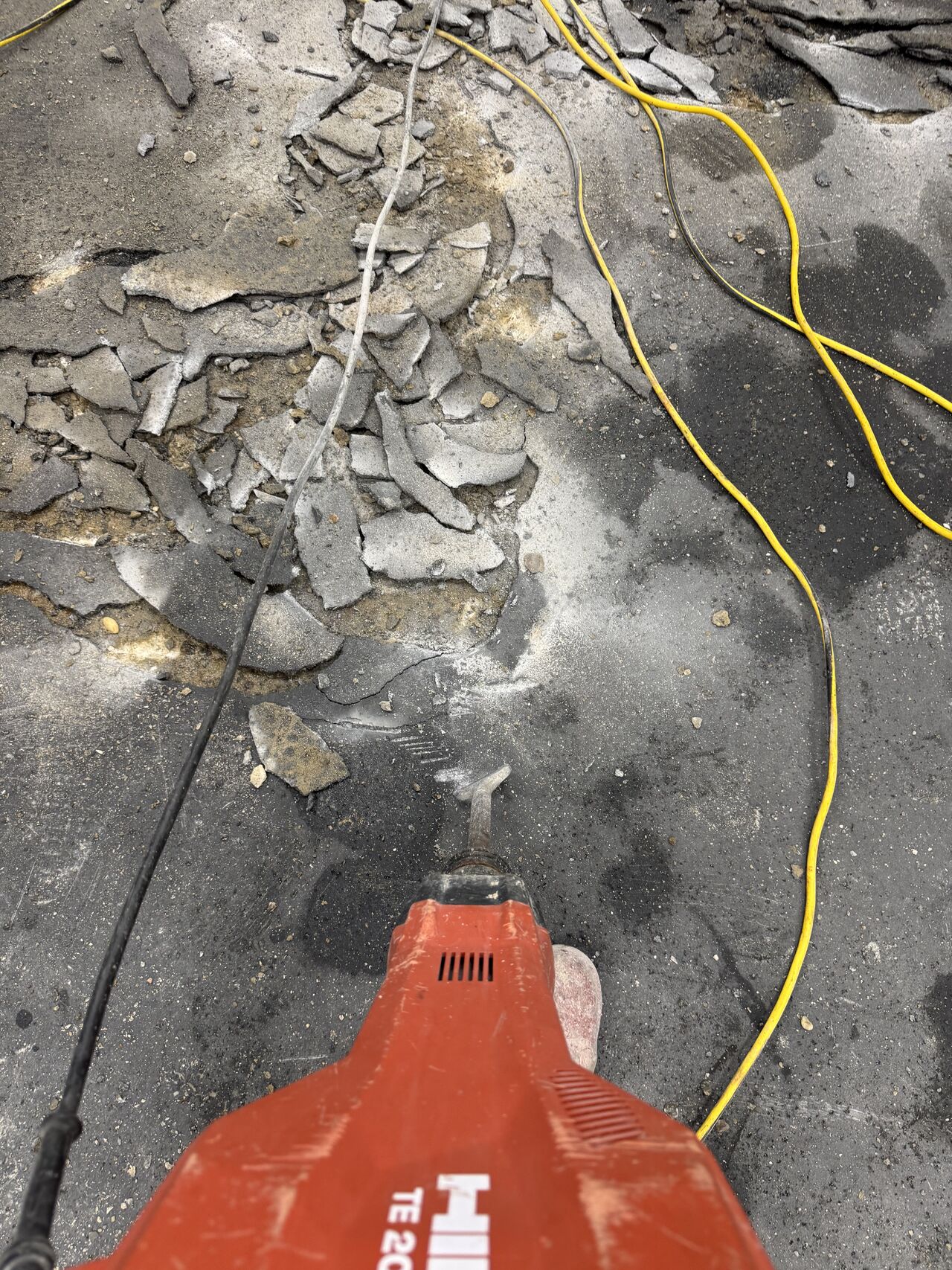 Wide view of demolished floor with debris and yellow extension cords across production area