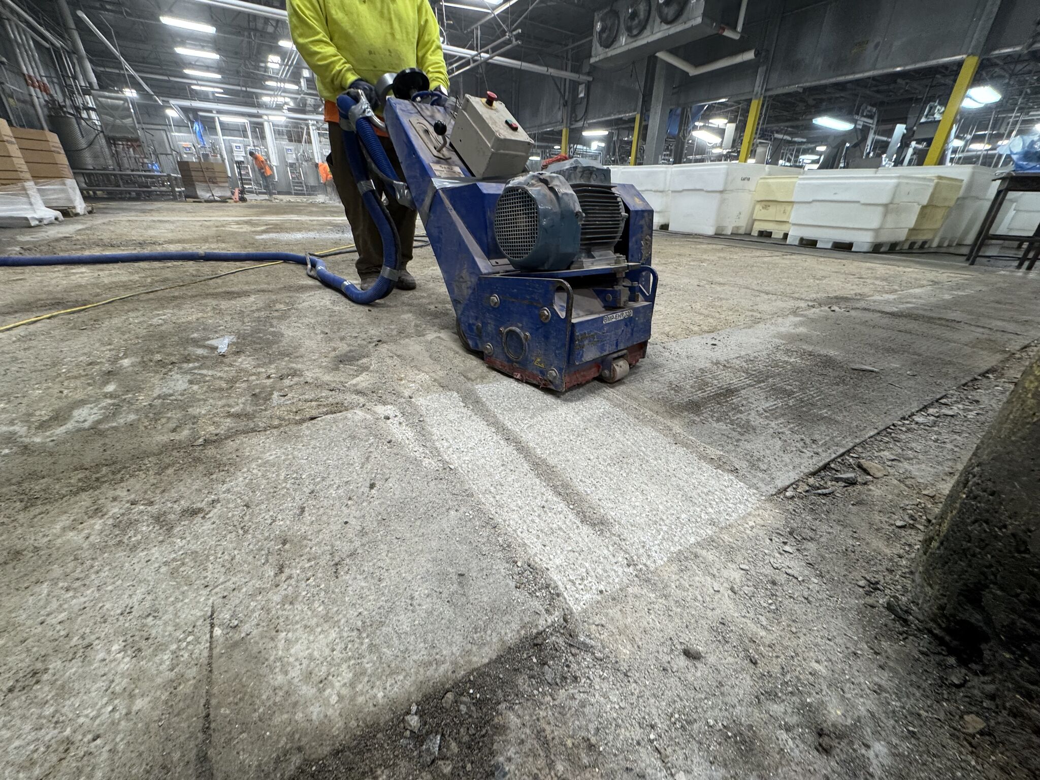 Crew member operating a scarifier to grind and profile the concrete substrate