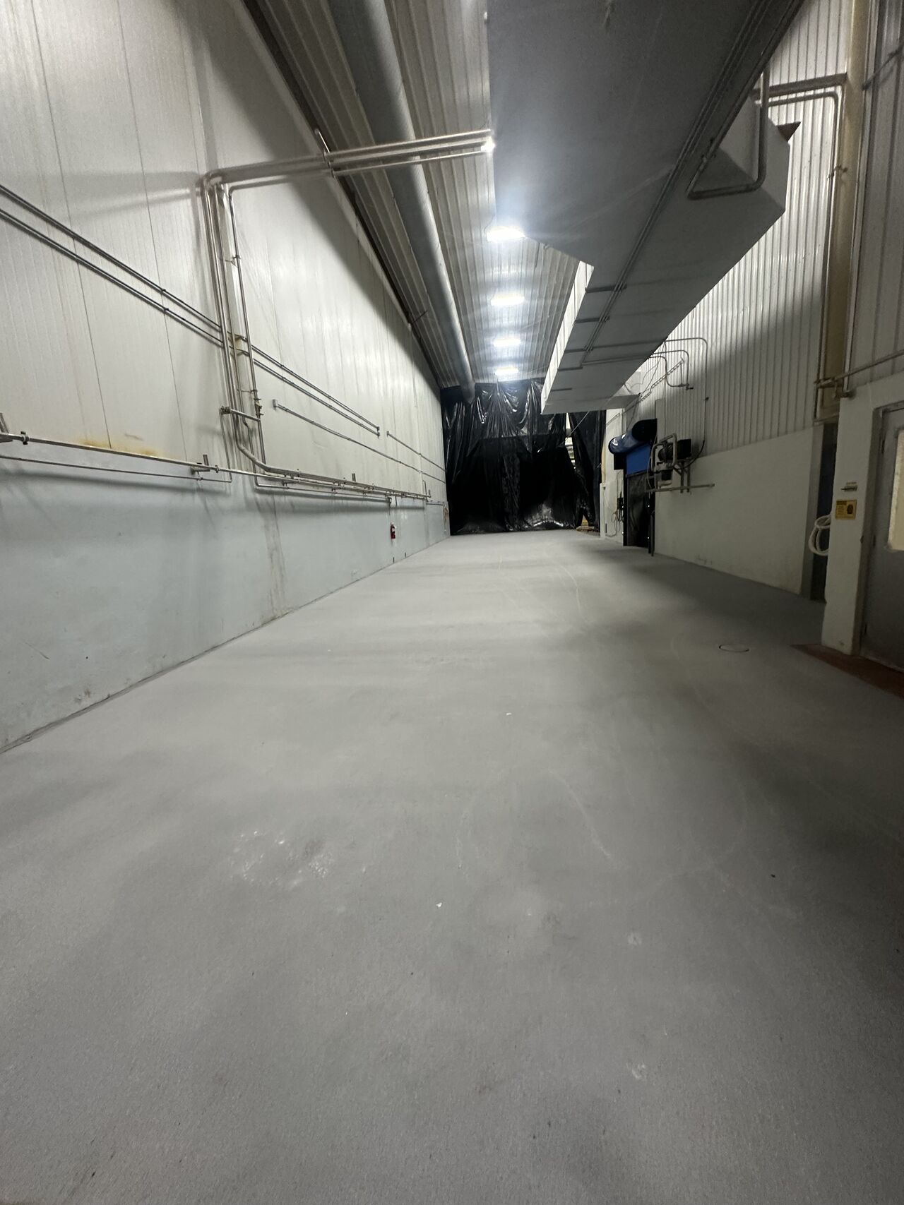 Gray SaniCrete STX floor in processing facility hallway with piping and ductwork